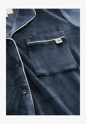 Navy blue, soft fabric pajama shirt with white piping along the collar and pocket. Features buttons and a left chest pocket.