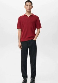 Rød, kortærmet polo med V-hals, kombineret med sorte skræddersyede bukser og mørke sko. Glat tekstur, enkelt design og tætsiddende snit.