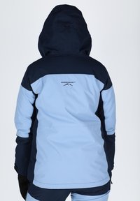 Niebieska i granatowa kurtka narciarska z kapturem, charakteryzująca się gładką fakturą, regulowanymi mankietami i logo na plecach.