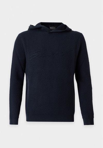 Sweat à capuche bleu marine texturé à manches longues avec une écriture discrète en relief sur la poitrine.