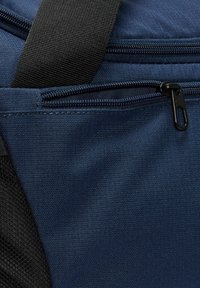 Sac en tissu bleu marine avec une surface texturée, accent en maille noire et fermeture éclair avec tirette noire.