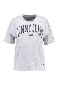 Camiseta de algodón gris de manga corta, con "TOMMY JEANS" impreso en azul oscuro y un pequeño detalle de logo en el dobladillo.