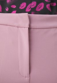 Pink pants featuring a smooth, textured fabric, with a flat waistband and small side pocket detail. Background includes a pattern in black and pink.