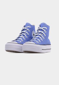 Ζευγάρι μπλε Converse μποτάκια ψηλού πάτου με λευκά κορδόνια και χοντρές λευκές σόλες, τοποθετημένα διαγώνια σε λευκό φόντο.