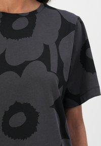 Gray t-shirt with a large black floral pattern, round neckline, and short sleeves. Made from soft cotton material.