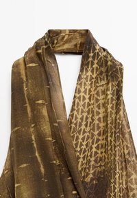 Écharpe marron à motifs comprenant un mélange de designs abstraits et de rayures, fabriquée en tissu doux et léger avec une texture lisse.