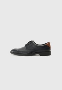 Chaussures à lacets pour hommes en cuir noir avec un bout rond, dotées d'un accent en cuir marron au talon et d'une semelle en caoutchouc noir basse.