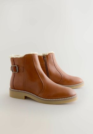 Bruine leren enkellaarsjes met een nepbontvoering, zijrits en een decoratieve band met een gesp; platte rubberen zool.