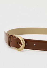 Rjav usnjen pas z gladko teksturo, opremljen z velikim okroglim zlatim sponkom in enakomerno razporejenimi luknjami za prilagajanje.