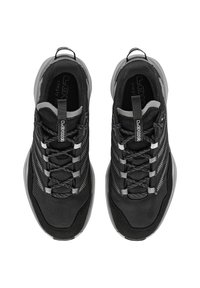 Schwarze Sportschuhe mit strukturiertem Stoff, reflektierenden Akzenten und robusten Schnürsenkeln, ausgestattet mit Polsterung und einer abgerundeten Sohle.