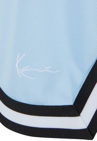 Lyseblå sports-trøje med mesh-textur, sorte og hvide accenter samt et broderet logo i hvidt nederst til venstre.