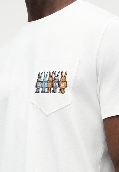 Λευκό βαμβακερό T-shirt με τσέπη στο στήθος, διακοσμημένη με κεντητές εικόνες πέντε καρτούν κουνελιών σε διάφορα χρώματα: καφέ, γκρι και μπλε.