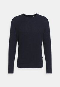 Pull en tricot bleu marine à manches longues, col rond et tissage texturé. Il présente un ourlet plat et une petite étiquette sur le côté.