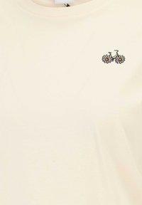 Cream-colored cotton t-shirt with a crew neck and short sleeves, featuring a small bicycle and daisy embroidery on the left chest.