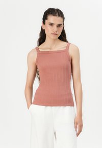 Vaaleanpunainen ribbitekstuuriinen tank top, jossa on neliömäinen kaula-aukko ja ohuet olkaimet, valmistettu joustavasta neulekankaasta, joka luo istuvan siluetin.