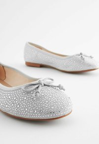 Graue Ballerinas mit einer strukturierten Oberseite, die mit kleinen Strasssteinen verziert ist, rundem Zehenbereich und einer dekorativen Schleife an der Vorderseite.