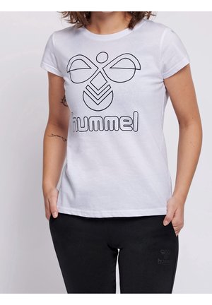 Personne portant un t-shirt blanc avec un grand logo hummel noir et un pantalon noir avec un petit logo hummel sur la cuisse gauche.