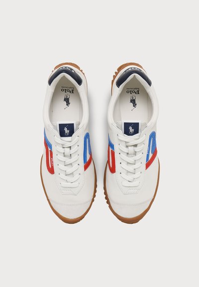 Ζευγάρι λευκά αθλητικά παπούτσια Polo Ralph Lauren με κόκκινες και μπλε πλευρικές ρίγες, λευκά κορδόνια και καφέ λαστιχένιες σόλες, εμφανιζόμενα από πάνω.