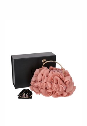 Bolso rosa con volantes y estampado floral, con asa de armazón dorada, expuesto junto a una caja de regalo negra y joyas a juego en tono dorado.