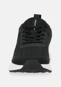 Scarpa da atletica nera con tomaia in mesh, dettagli testurizzati, design con lacci e suola bianca. Presenta un'etichetta con la scritta "SWEDEN".