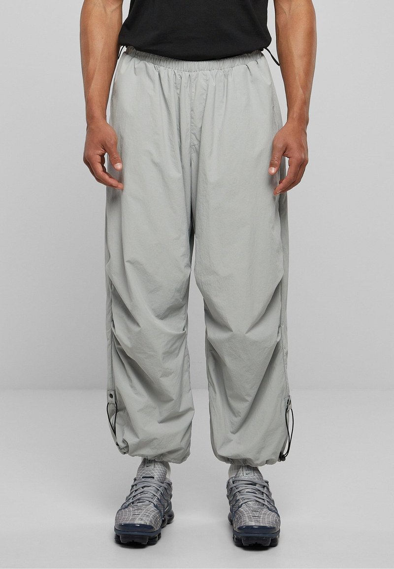 Jasnoszare spodnie cargo z elastycznym pasem, ściągaczami przy kostkach i bocznymi kieszeniami. Wykonane z lekkiego, oddychającego materiału.