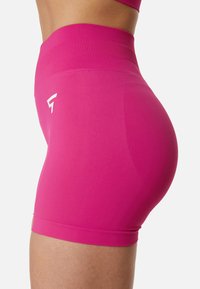 Ružové priliehavé atletické kraťasy s vysokým pásom, hladkou textúrou a malým bielym logom na boku. Detailný bočný pohľad.