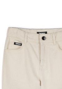 Jean en denim beige au design droit, avec surpiqûres, poches frontales et logo DKNY sur la ceinture.