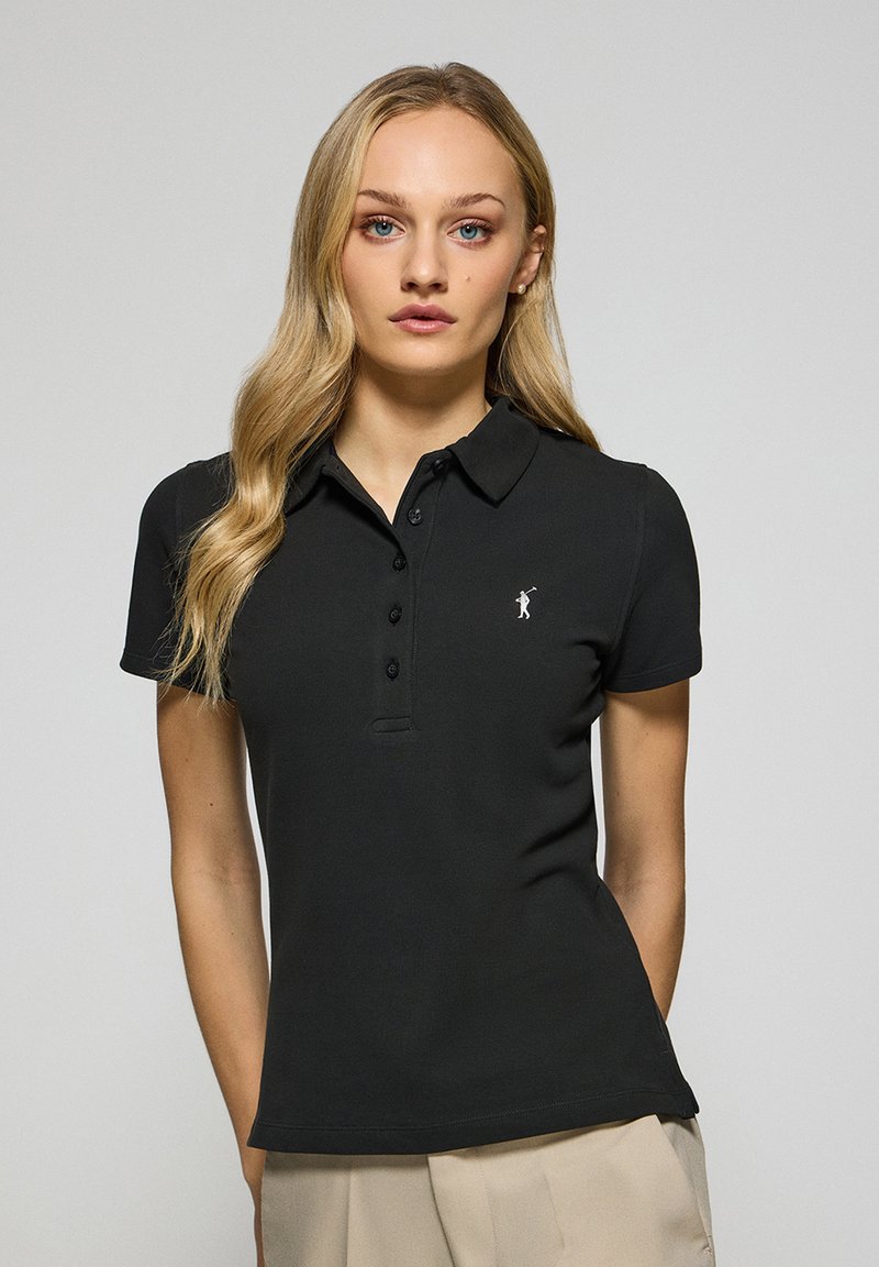 Svart pikétröja i bomull, med krage, korta ärmar och knappstängning fram. Litet logo på bröstet.