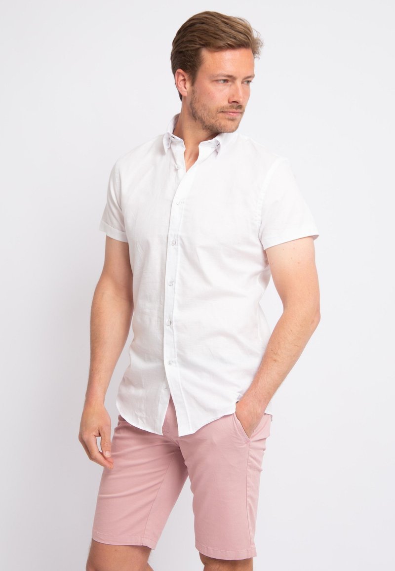 Korte mouwen, button-up shirt van witte stof met een klassieke kraag, gecombineerd met lichtroze shorts. Glad materiaal, getailleerde pasvorm.