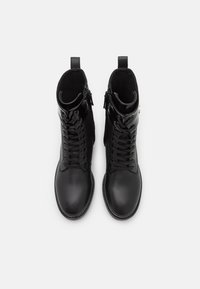 Stivaletti alla caviglia in pelle nera con superficie liscia, dotati di lacci, cerniera laterale e punta rotonda. La fodera interna è morbida e nera.