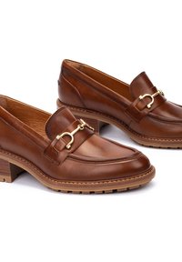 Mocasines de cuero marrón con detalle de hebilla dorada, parte superior texturizada y tacón apilado. Presentan un acabado suave y un diseño de puntera redonda.