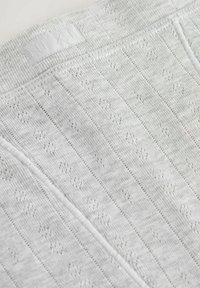 Il tessuto lavorato a maglia grigio presenta un motivo a righe con piccoli disegni in pizzo aperto. Include un'etichetta con il nome del marchio "NEXT" in vita.