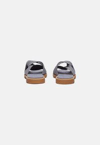Gray fabric sandals with cross-over straps, soft insoles, and a tan rubber sole, featuring a textured design and open back.