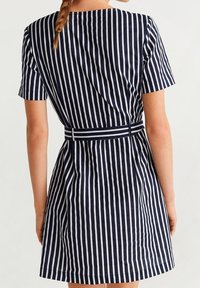 Sukienka w granatowo-białe paski z krótkimi rękawami, dopasowaną talią i rozkloszowanym dołem. Wykonana z gładkiego materiału z wyraźnym szwem z tyłu.