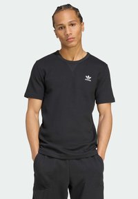 Μαύρο κοντομάνικο μπλουζάκι φτιαγμένο από υφασμάτινη ύφανση, με στρογγυλή λαιμόκοψη και μικρό λευκό λογότυπο Adidas στο στήθος.