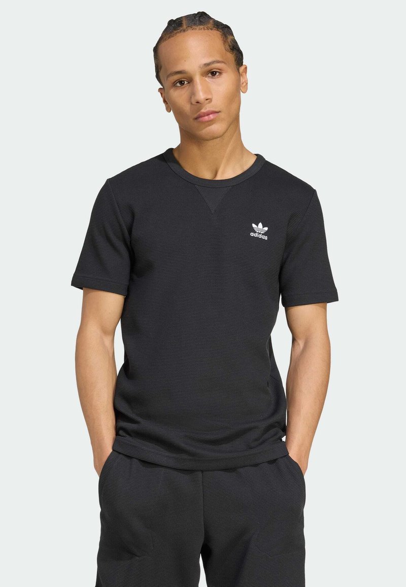 Μαύρο κοντομάνικο μπλουζάκι φτιαγμένο από υφασμάτινη ύφανση, με στρογγυλή λαιμόκοψη και μικρό λευκό λογότυπο Adidas στο στήθος.