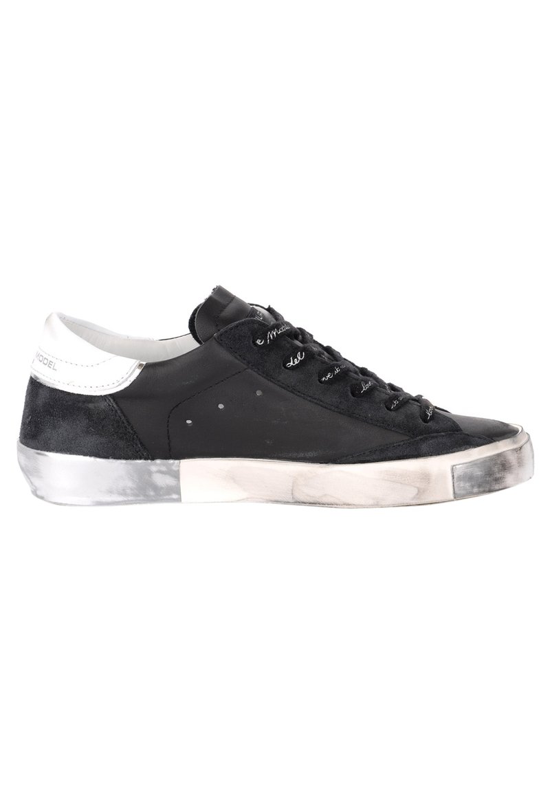 Baskets noires en matériaux daim et cuir, avec une semelle intermédiaire texturée, un design à lacets et une touche de blanc au niveau du talon.