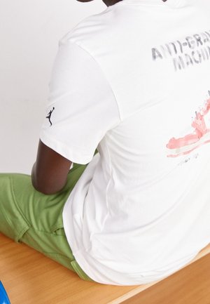 Hvid kortærmet t-shirt med "ANTI-GRAVITY MACHINE" grafik i grå og rød på ryggen, med et sort Jumpman-logo på ærmet.