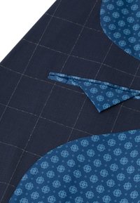 Granatowy materiał w kratę zawiera niebieską okrągłą część z kwiatowym nadrukiem. Zawiera trójkątną kieszeń w pasującym materiale.