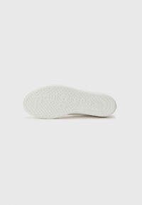 Semelle de sneaker blanche avec un motif de grip texturé et le nom de la marque "Paul Green" en relief. Fini lisse, forme arrondie, design minimaliste.