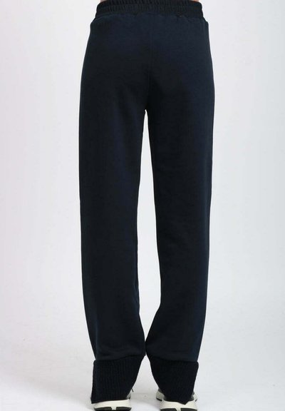 Pantaloni della tuta blu navy con vita e polsini a costine, caratterizzati da una vestibilità ampia e una texture del tessuto liscia. Nessun dettaglio aggiuntivo visibile.