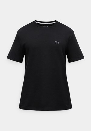Melns īsām piedurknēm T-krekls no strukturētas kokvilnas, ar mazu baltu Lacoste logo uz kreisās krūtis un apaļu kakla izgriezumu.