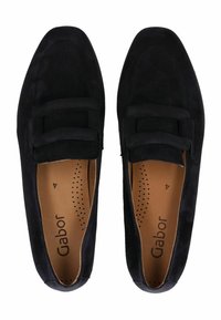 Mocasines de ante negro con una textura suave, que cuentan con una correa ancha en la parte frontal y una plantilla acolchada. El interior presenta un diseño perforado.
