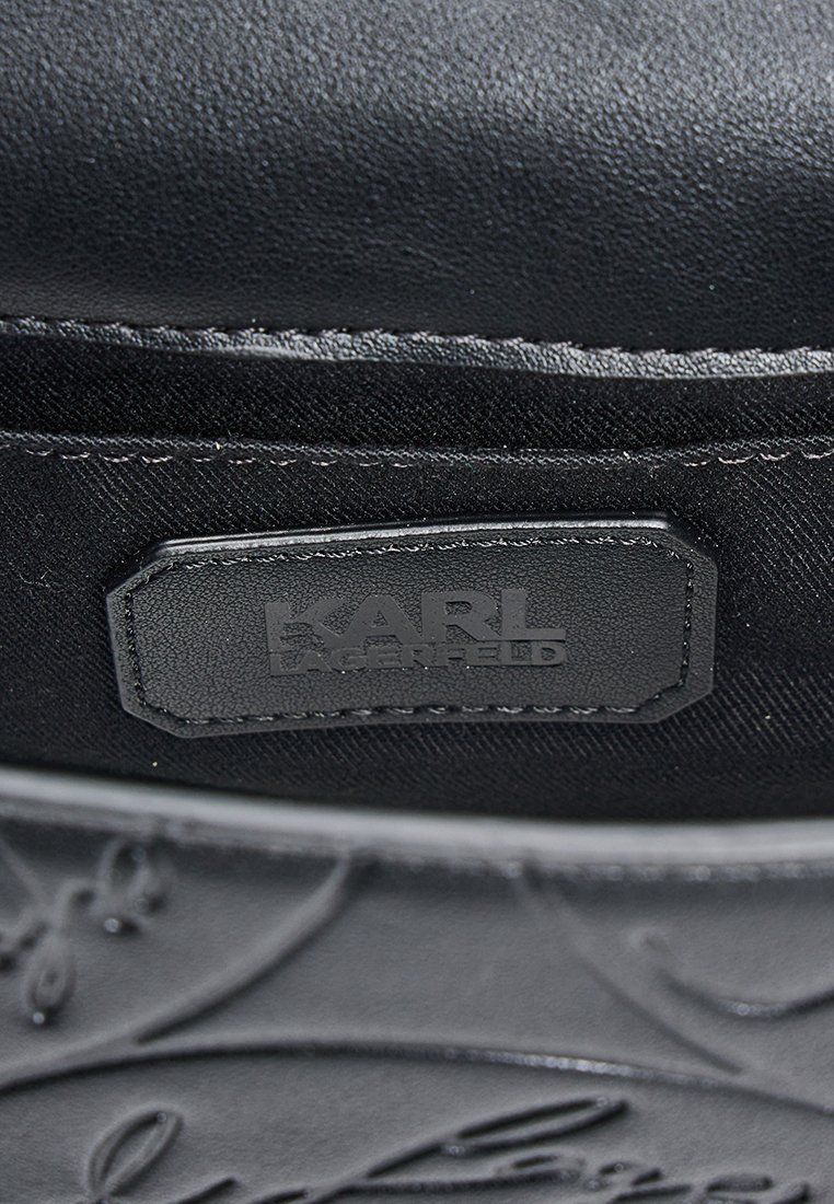 Interno di una borsa in pelle nera e tessuto con un'etichetta rettangolare cucita e impressa con il nome del marchio "KARL LAGERFELD".