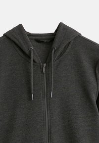 Grijze hoodie met rits, gemaakt van gestructureerd materiaal. Voorzien van een capuchon, trekkoorden en een frontrits. Eenvoudig ontwerp zonder zichtbare patronen.