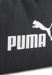 Borsa Puma in tessuto nero con un logo bianco prominente e un design elegante. La superficie testurizzata con motivi sottili aggiunge dettaglio.