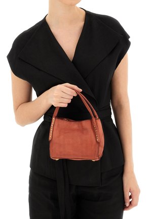 Borsa a tracolla in pelle marrone con borchie dorate ai lati, forma rettangolare e manici corti. Indossata da una persona con una maglietta nera.