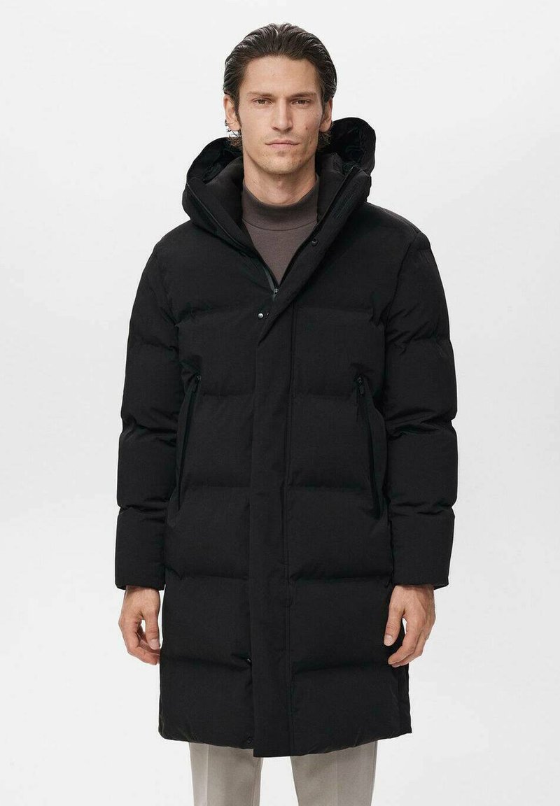 Abrigo acolchado negro con capucha, que presenta un cierre de cremallera, dos bolsillos laterales y un diseño acolchado para aislamiento. Textura suave y mate.