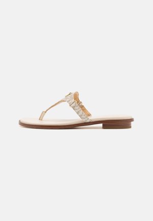 Sandalia plana beige con un tacón bajo de madera, tira entre los dedos y una correa texturizada en el tobillo con detalle de hebilla dorada.