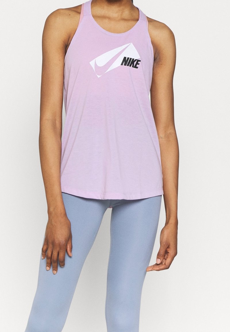 Personne portant un débardeur Nike violet clair et un legging bleu clair, debout les bras relâchés le long du corps.